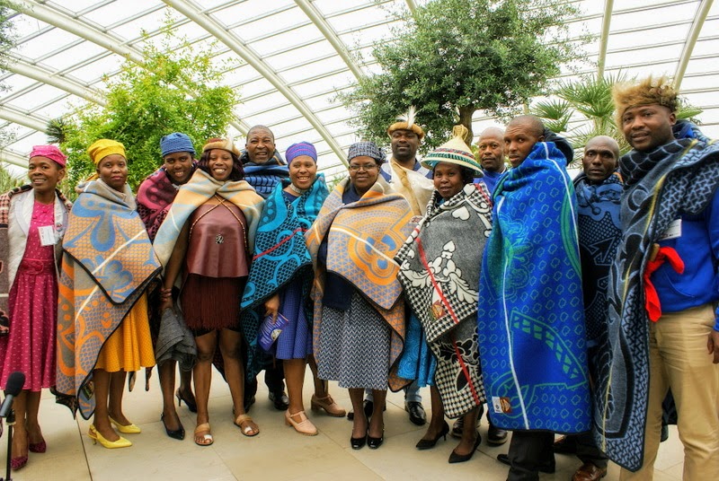 A group of 13 people, all wearing colourful blankets/shawls.