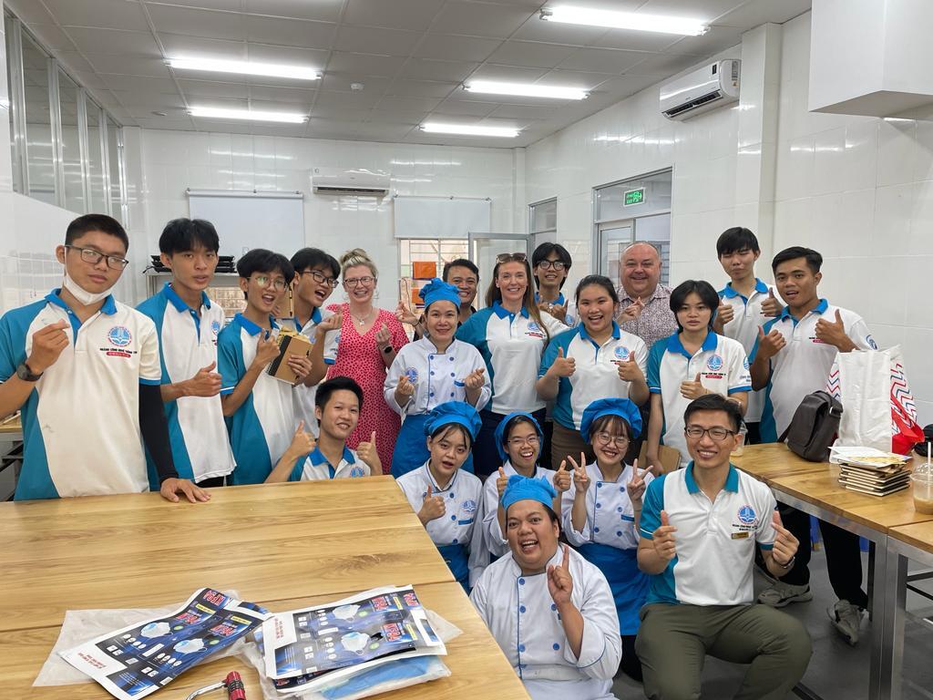 Group of students and teachers, some students are wearing blue and white t-shirts and others wearing blue and white chef uniforms.