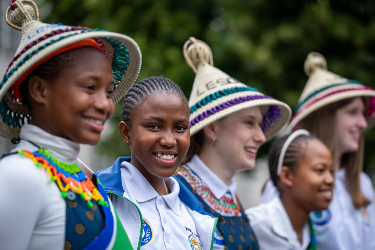 A line of people smiling and laughing. Some are wearing Basotho (mokorotlo) hats.