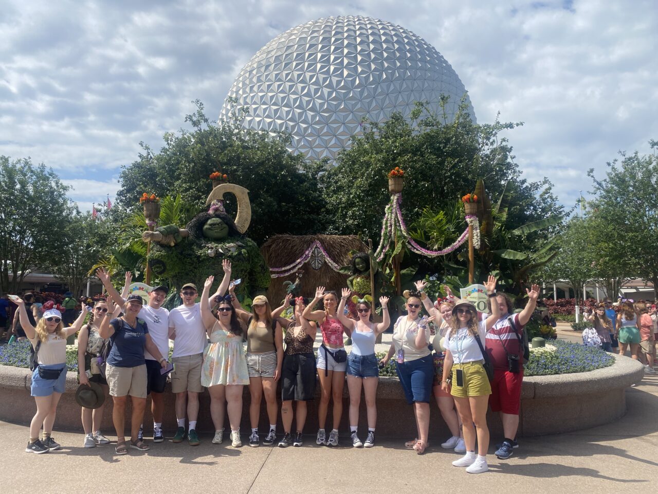 Myfyrwyr a staff PCYDDS yn sefyll am lun o flaen arddangosfa flodau o Moana a Maui Disney.